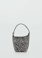 Bolso tipo bucket con estampado de cebra en blanco y negro, asa corta rígida, cierre magnético y forro interior.