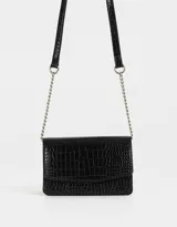 Bandolera negra de cuerina con textura croco, solapa con broche a presión y correa de cadena metálica plateada con charm lateral.