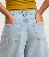 Pantalón de jean celeste, modelo barrel, con trabillas en la cintura, bolsillos y detalle de recorte en la entrepierna.