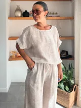 Pantalón ancho de tiro alto, color beige claro con textura, confeccionado en tela crepé. Presenta cintura elástica con cordón ajustable.