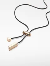 Collar con cordón negro ajustable y dije metálico dorado con grabados.