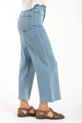 Jean de mezclilla azul claro, tiro medio, corte recto con leve campana al tobillo. Presenta costuras verticales marcadas en el frente y en los laterales de las piernas, y terminación deshilachada en el ruedo.