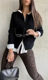 Campera negra de hilo con cierre frontal y detalle de trenzas en los hombros.