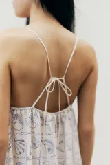 Vestido largo con estampado de motivos marinos en tonos azules, escote en V y tirantes finos que se cruzan en la espalda.