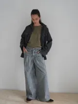 Pantalón vaquero de corte ancho, color crudo, con cintura alta y detalle de costuras cruzadas en la parte superior.