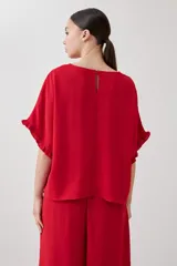 Blusa roja de manga corta con volados en los puños y cuello redondo.