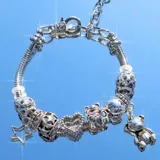 Pulsera plateada de eslabones con cierre de mosquetón y dijes colgantes con forma de estrella, corazón y oso.