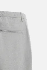 Pantalón negro de corte slim fit, confeccionado en tejido elástico. Cuenta con cintura elástica, bolsillos frontales y traseros de vivo. Cierre frontal con cremallera y botón.