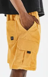 Bermuda cargo color mostaza de corderoy liviano, con bolsillos amplios con solapa, fuelle y detalles en cinta gross, elástico en la cintura y calce oversize.