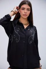 Camisa negra de manga larga con detalles de lentejuelas y bordados en el pecho, cuello camisero y cierre de botones.