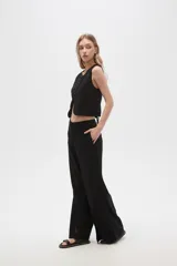 Pantalón negro ancho de lino y viscosa, de tiro alto y corte palazzo con aberturas en el ruedo.