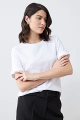 Remera blanca de manga corta con cuello redondo y botón metálico en los puños.