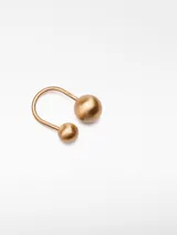 Anillo tipo torque dorado con esferas metálicas en los extremos y logo grabado.