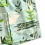 Short de baño celeste con estampado de hojas verdes y formas geométricas en blanco y negro. Tiene elástico en la cintura, cordón ajustable y tres bolsillos.