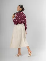 Falda midi de corderoy color beige claro, con pliegues verticales marcados y cintura elastizada. Incluye un cinturón desmontable de cuero marrón con hebilla dorada.