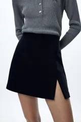 Falda pantalón negra de tiro alto con abertura frontal y cierre lateral con cremallera oculta.