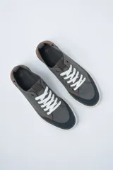 Zapatillas acordonadas de lona color gris con detalles en marrón y azul marino. Suela de goma blanca.