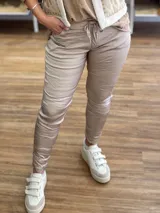 Pantalón de viscosa satinada color beige, con elástico y cordón ajustable en la cintura, corte ajustado y efecto arrugado.