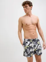 Short de baño con estampado floral en tonos blanco, verde y marrón sobre fondo azul oscuro. Cuenta con cintura elástica, cordón ajustable, bolsillos laterales y trasero.