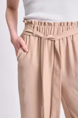 Pantalón color beige de corte ancho, con lazo ajustable en la cintura.
