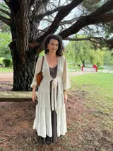 Túnica larga de gasa color beige claro, con mangas largas y cuello en V, con detalle de amarre frontal.