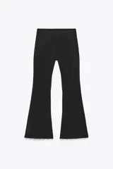 Pantalón negro de tiro alto, corte ajustado y cintura elástica. El ruedo es acampanado y está decorado con perlas.