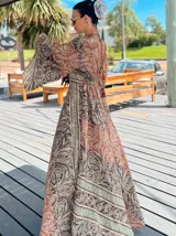 Vestido largo de polysilk con estampado paisley en tonos azul, celeste y dorado. Tiene escote en V, mangas largas acampanadas y corte amplio.