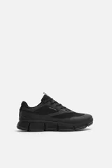 Zapatillas deportivas negras con capellada de tejido técnico transpirable y suela gruesa.