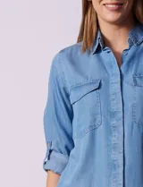 Camisa celeste de tencel con cuello con solapa, abertura central con botones ocultos, bolsillos delanteros y mangas largas regulables con presilla y botón.