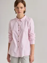 Camisa celeste de algodón con cuello clásico, cierre frontal con botones y mangas largas. Presenta volados en el frente y corte evasé.