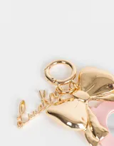 Llavero con dije de espejo en forma de corazón con borde rosa, moño dorado y dije con la palabra "Lucky".