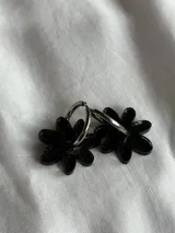 Par de aros colgantes con forma de flor negra con glitter y argolla plateada.