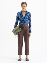 Pantalón negro de tiro alto, estilo mom fit, confeccionado en poplin con spandex. Presenta tablas en la cintura con cinto de hebilla de cadena dorada, canesú y pinzas delanteras.