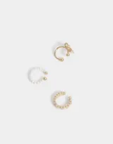 Set de tres earcuffs dorados, uno con perlas blancas, otro con un moño y otro con corazones.