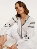 Blusa blanca de manga larga con bordados negros en cuello, mangas y frente.
