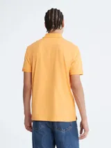 Chomba color naranja de manga corta, con cuello polo y tapeta de dos botones. Tiene el logo de Calvin Klein bordado en el pecho. Corte regular.