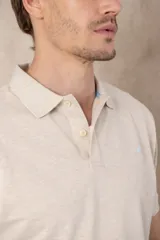 Chomba azul marino de piqué con cuello clásico, tapeta de dos botones y logo de pájaro bordado en color rosa en el pecho.