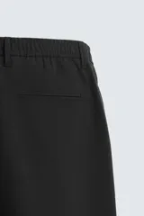 Pantalón largo de vestir gris claro con estampado de cuadros, corte slim fit y cintura elástica. Confeccionado en tejido con alta elasticidad, bolsillos frontales y cierre frontal con cremallera y botón.
