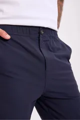 Pantalón de vestir azul marino, de corte recto, con bolsillos laterales y traseros. Se ajusta a la cintura con cinturón de cuero marrón.
