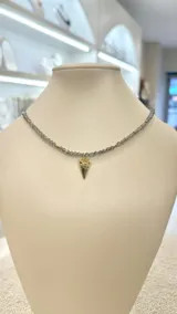 Collar corto de cristal facetado color gris, con pequeños detalles dorados y dije de corazón dorado con un ojo en el centro.