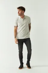 Remera polo negra de manga corta con cuello clásico, cierre de botones, bolsillo en el pecho y logo estampado.