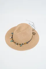 Sombrero de paja tejido color caqui, con ala ancha y copa tipo fedora. Está decorado con una cinta negra adornada con cuentas de madera, dijes turquesa en forma de hoja y dije de caracol.