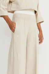 Pantalón de corte amplio color beige, con detalle de alforza central, recortes laterales y cintura elastizada en la espalda. Amplios bolsillos. Marca Zettia.
