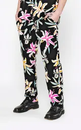 Pantalón recto unisex con estampado floral en tonos rosa, amarillo, celeste y blanco sobre fondo negro. Confeccionado en rayón.