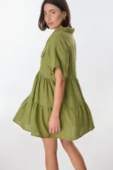 Vestido corto celeste de lino, con cuello tipo polo con detalle de puntilla, mangas cortas y falda escalonada con volantes.