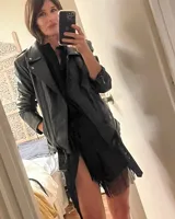 Campera biker negra de cuero ovino con cuello solapa, cierre asimétrico con cremallera, bolsillos con cremallera y cinturón ajustable en la cintura.