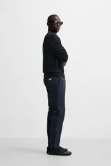 Pantalón chino azul marino, corte skinny fit, confeccionado en tejido de algodón con elasticidad. Cuenta con bolsillos frontales y traseros de vivo. Cierre frontal con cremallera y botón.