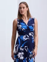Vestido largo de seda fría con estampado floral en tonos azul y blanco. Tiene escote en V cruzado, cintura con faja plisada y detalles con relieve.