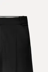 Pantalón negro de tiro alto con pinzas delanteras, corte ancho y largo midi.