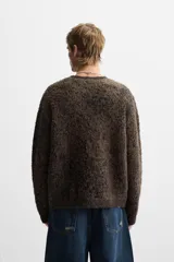 Jersey marrón con diseño jacquard pixelado en negro, de corte relaxed, cuello redondo y manga larga con terminaciones en rib.